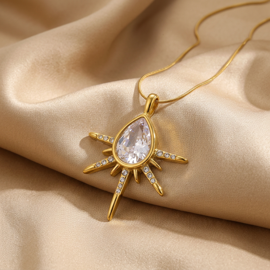 Sunburst teardrop pendant and gold-tone snake chain on champagne silk