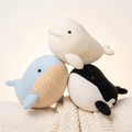 Three kawaii whale plushies in cozy dreamy huddle on warm white background