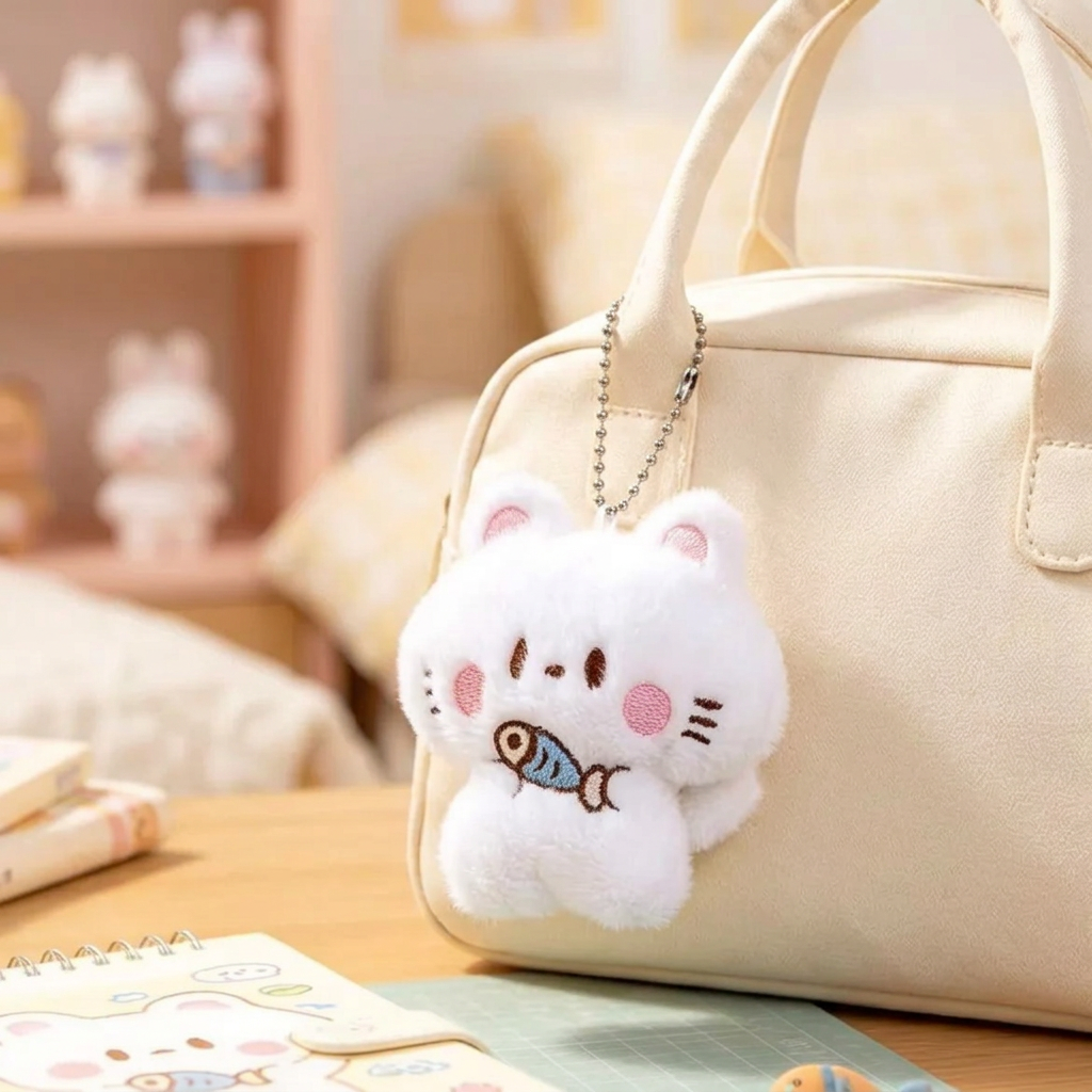 Kawaii plush kitten charm clipped to a cream bag - lifestyle shot