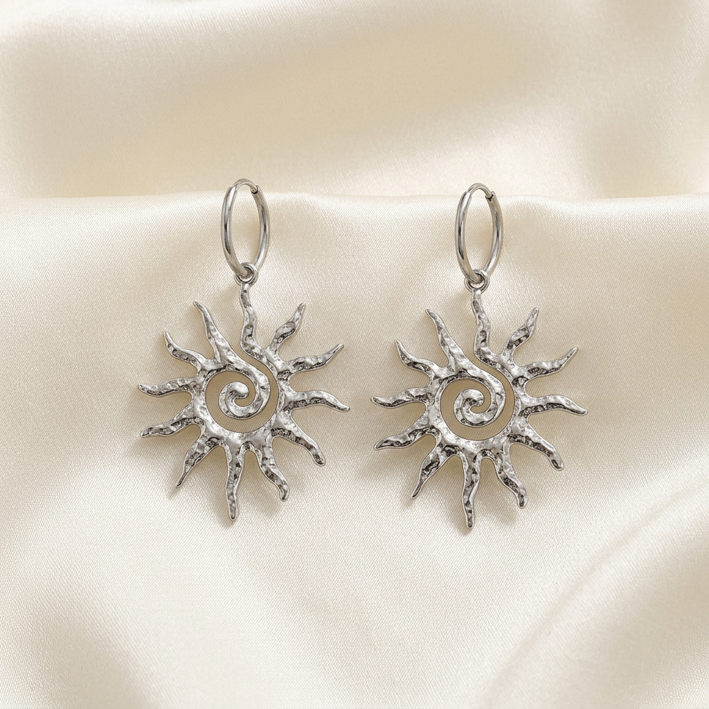 Pair of silver-tone spiral sun drop earrings on ivory silk