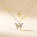 Gold-tone layered butterfly necklace on an ivory background
