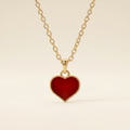 Red enamel heart necklace with gold-tone chain on ivory