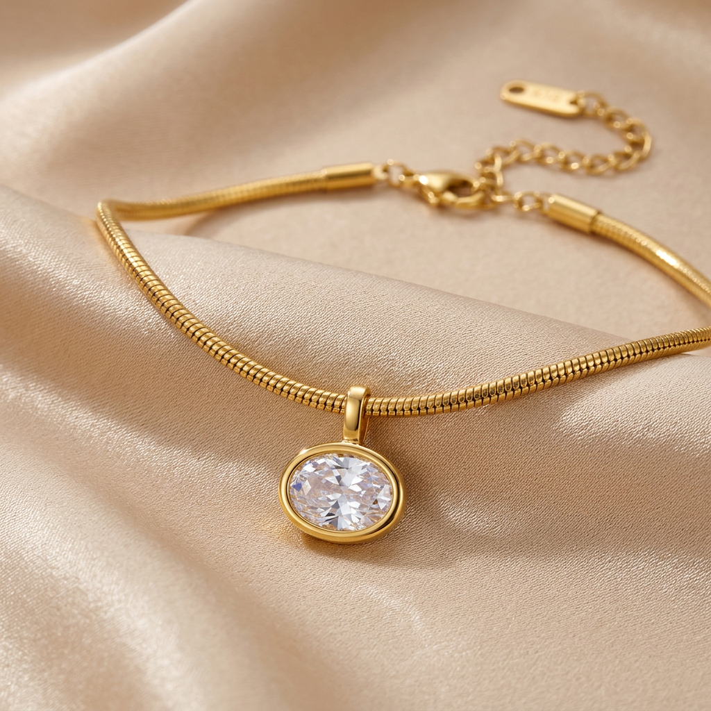 Gold-tone snake chain choker with oval bezel pendant on champagne silk